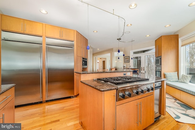 kitchen with light wood-style floors, recessed lighting, dark stone counters, and built in appliances