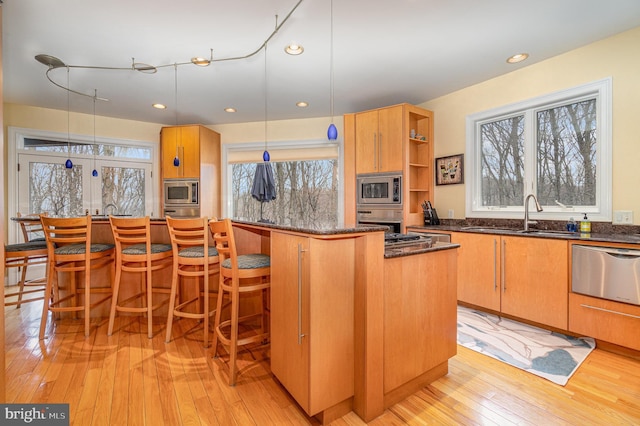 kitchen with stainless steel appliances, light wood-type flooring, open shelves, a sink, and a warming drawer