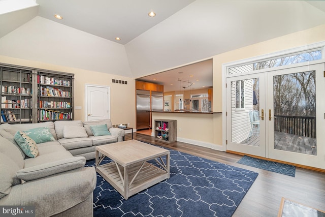 living area with high vaulted ceiling, plenty of natural light, and wood finished floors