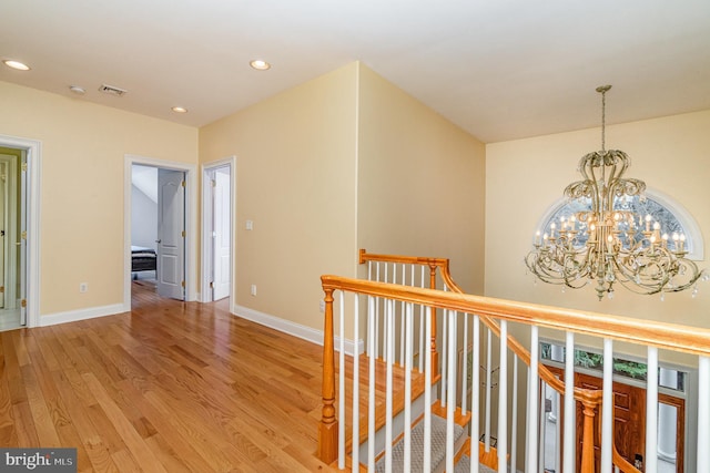 hallway featuring a chandelier, light wood-style flooring, recessed lighting, an upstairs landing, and baseboards