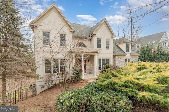 view of front of home featuring stone siding, fence, and stucco siding