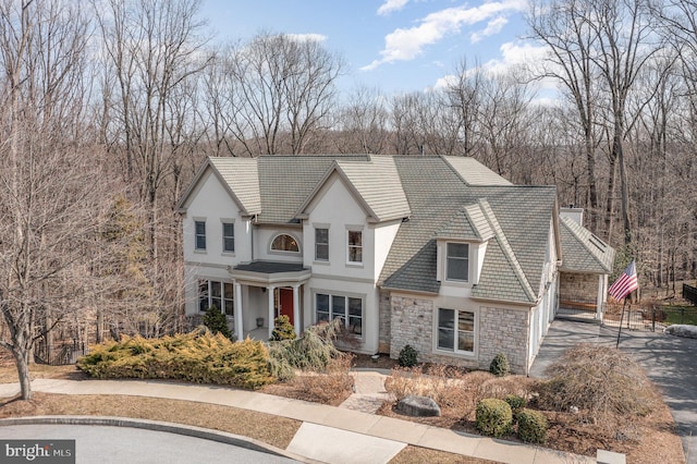 view of front of house with stone siding, a tiled roof, and stucco siding