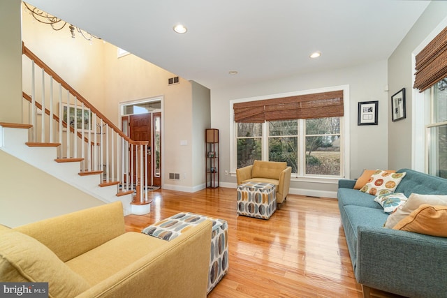 living area with recessed lighting, visible vents, baseboards, stairs, and light wood finished floors