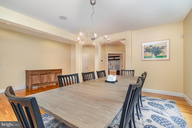 dining room featuring light wood-type flooring, baseboards, and an inviting chandelier