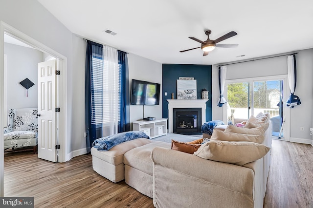 living area with visible vents, a fireplace, ceiling fan, and wood finished floors