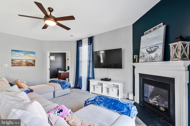 living area with a glass covered fireplace and a ceiling fan