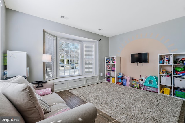 living area featuring visible vents and wood finished floors