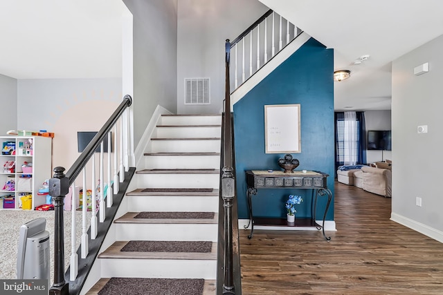 stairway with visible vents, baseboards, and wood finished floors