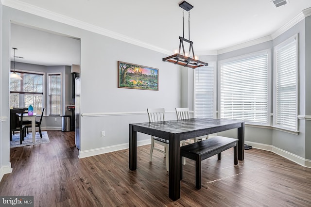 dining space with dark wood finished floors, crown molding, and baseboards