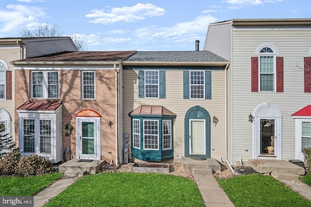 view of property with brick siding and roof with shingles