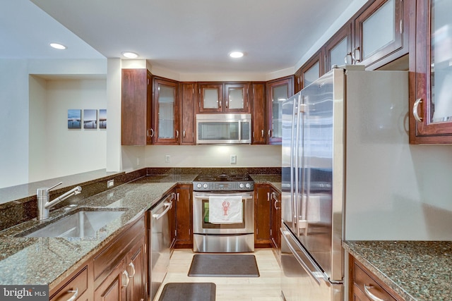 kitchen with a sink, dark stone countertops, recessed lighting, and stainless steel appliances