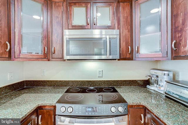 kitchen with brown cabinets, stainless steel appliances, and glass insert cabinets