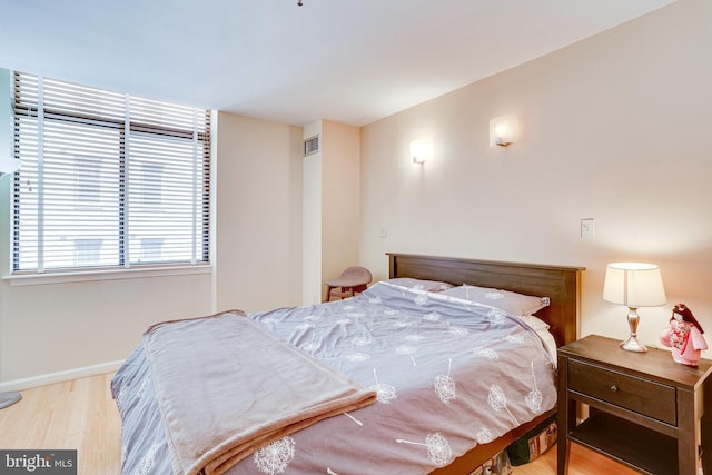 bedroom with visible vents, baseboards, and wood finished floors