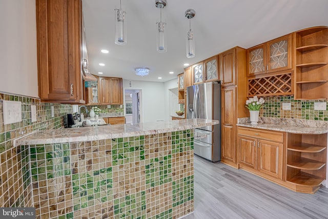 kitchen with open shelves, light wood finished floors, stainless steel fridge, and brown cabinets