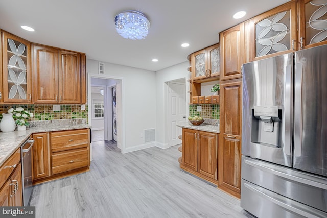 kitchen featuring appliances with stainless steel finishes, light stone countertops, visible vents, and tasteful backsplash