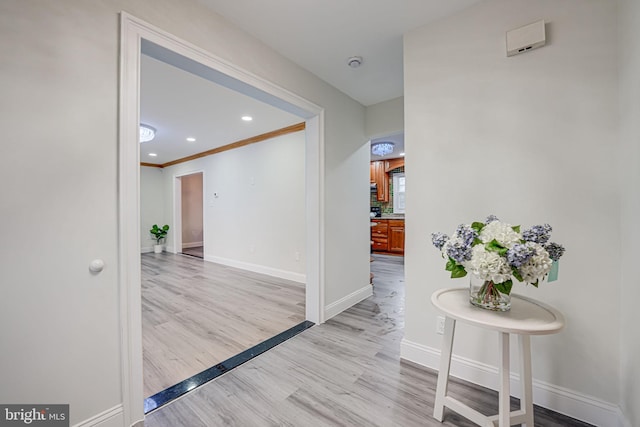 hallway with ornamental molding, recessed lighting, light wood-style flooring, and baseboards