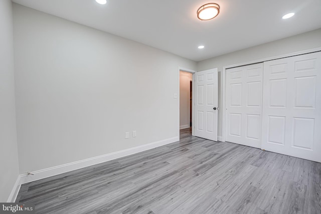 unfurnished bedroom with a closet, baseboards, wood finished floors, and recessed lighting