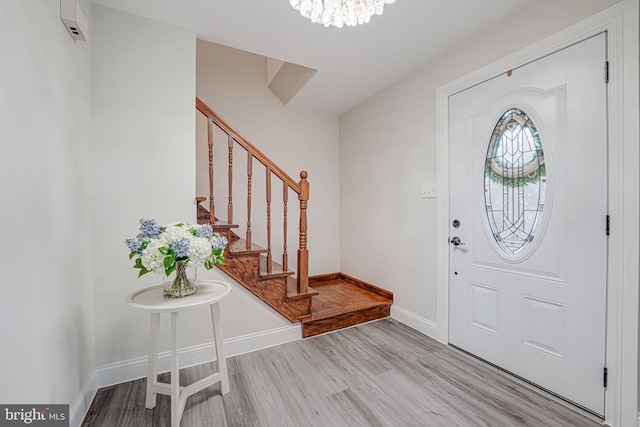 entrance foyer featuring light wood-type flooring, stairs, baseboards, and a chandelier