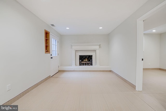 unfurnished living room with recessed lighting, a fireplace with raised hearth, visible vents, and baseboards