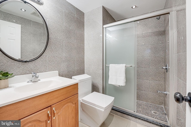 bathroom with toilet, recessed lighting, vanity, tile walls, and a shower stall