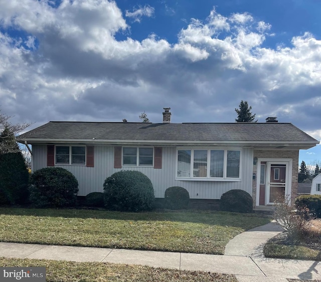 single story home featuring roof with shingles, a chimney, and a front yard