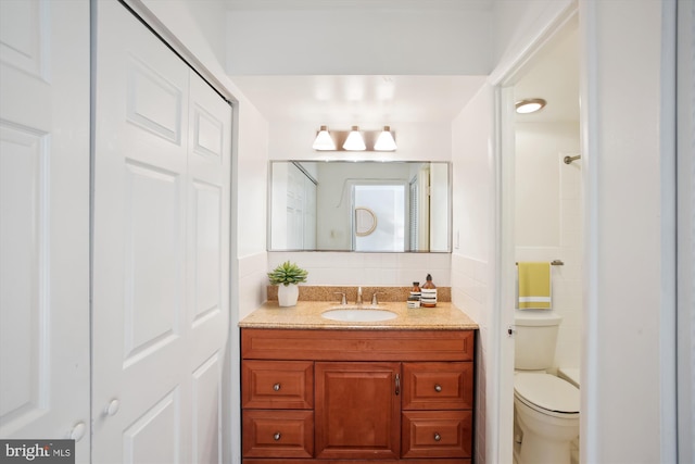 bathroom featuring a shower, vanity, toilet, and tasteful backsplash