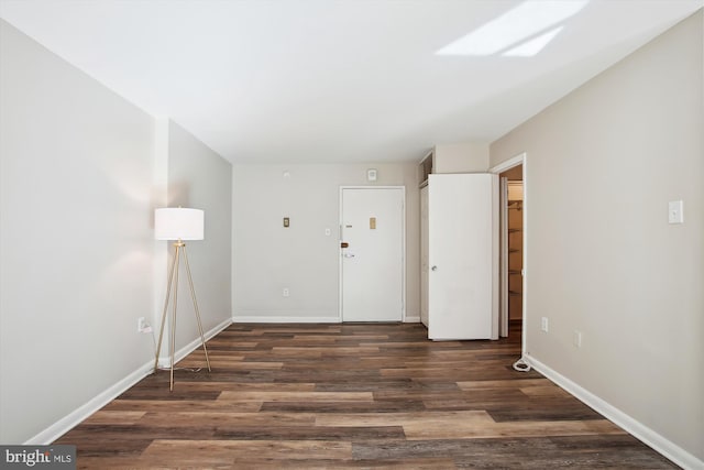 spare room with baseboards and wood finished floors