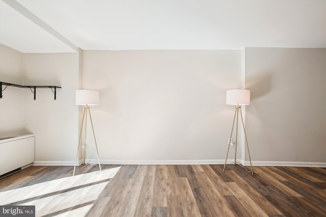 spare room with baseboards and wood finished floors