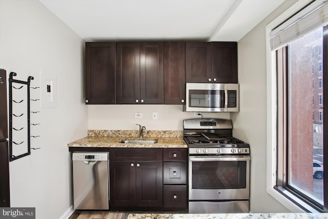 kitchen featuring stainless steel appliances, a sink, and dark brown cabinetry