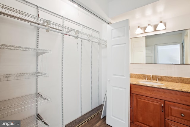 bathroom featuring wood finished floors, vanity, and decorative backsplash