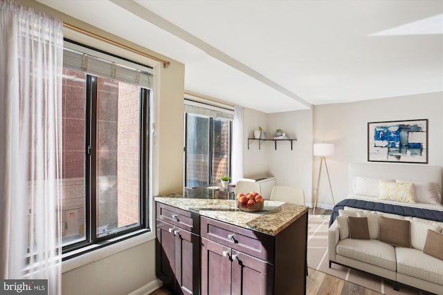 kitchen featuring light stone countertops, baseboards, open floor plan, and light wood-style floors