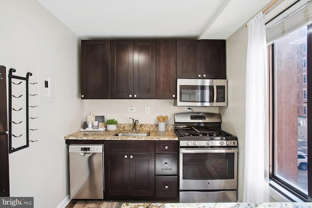 kitchen with appliances with stainless steel finishes, a sink, and dark brown cabinetry