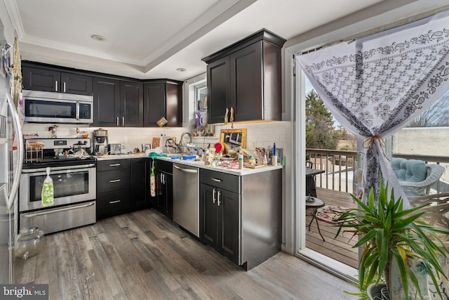 kitchen with decorative backsplash, dark wood-style floors, stainless steel appliances, light countertops, and a sink