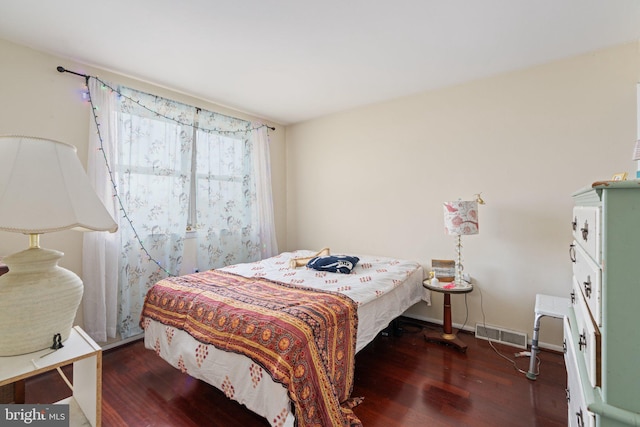 bedroom featuring baseboards, visible vents, and wood finished floors