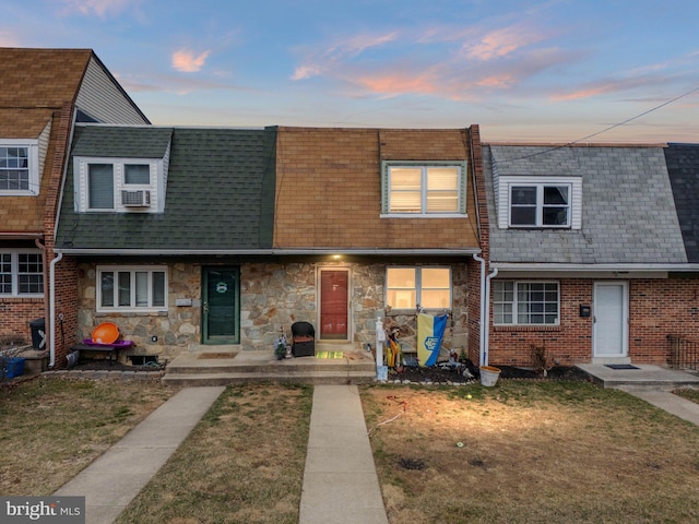 multi unit property featuring cooling unit, roof with shingles, a lawn, and brick siding