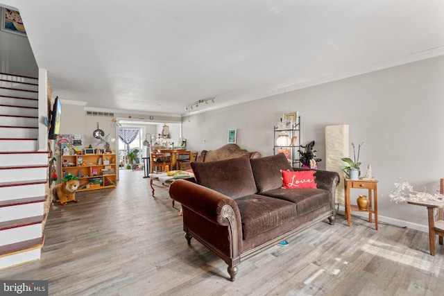 living room with stairs, wood finished floors, visible vents, and crown molding