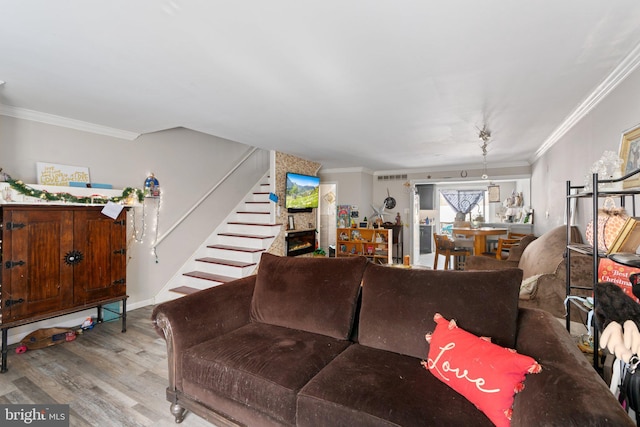 living room with crown molding, visible vents, stairway, and wood finished floors