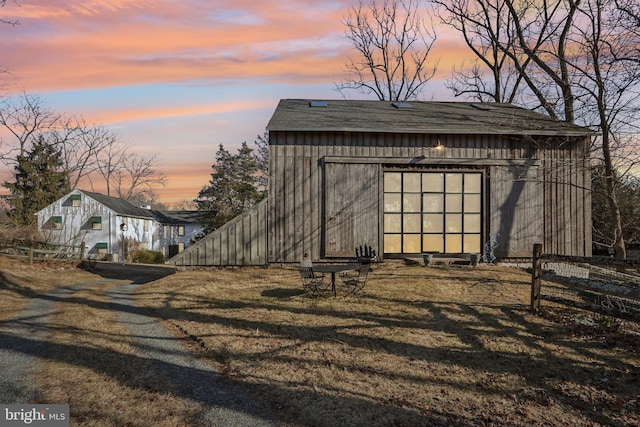 outdoor structure at dusk featuring an outdoor structure and fence