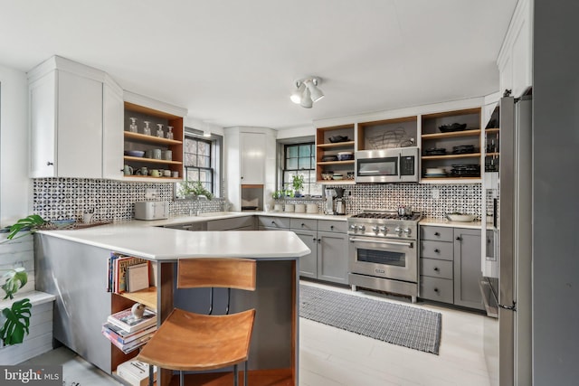 kitchen with open shelves, appliances with stainless steel finishes, and decorative backsplash