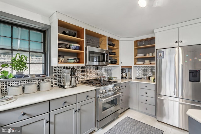 kitchen featuring stainless steel appliances, gray cabinets, open shelves, and decorative backsplash