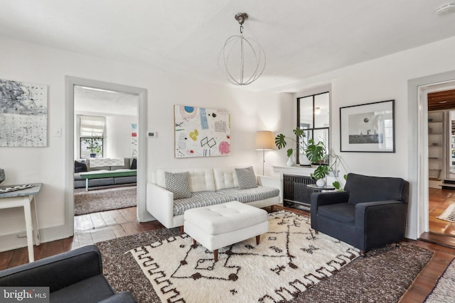 living area featuring a fireplace, radiator heating unit, and wood finished floors