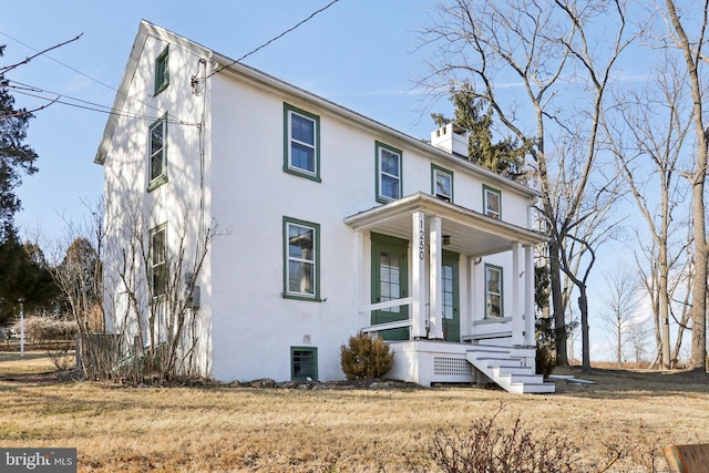 view of front of property with a porch, a chimney, and stucco siding