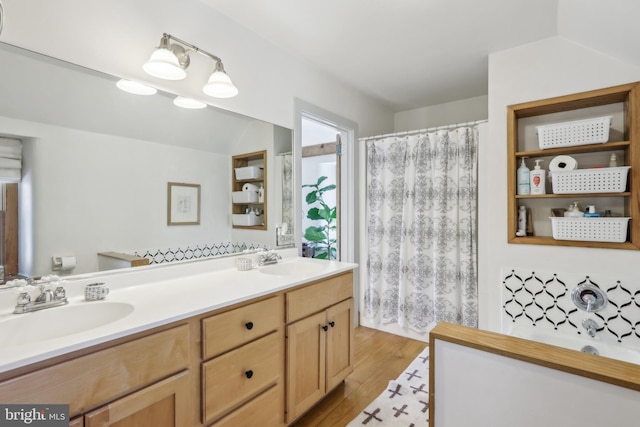 bathroom with double vanity, a washtub, a sink, and wood finished floors