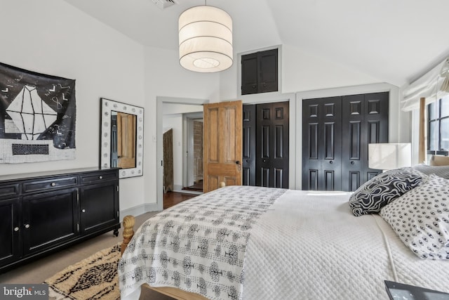 bedroom with lofted ceiling, two closets, visible vents, and baseboards