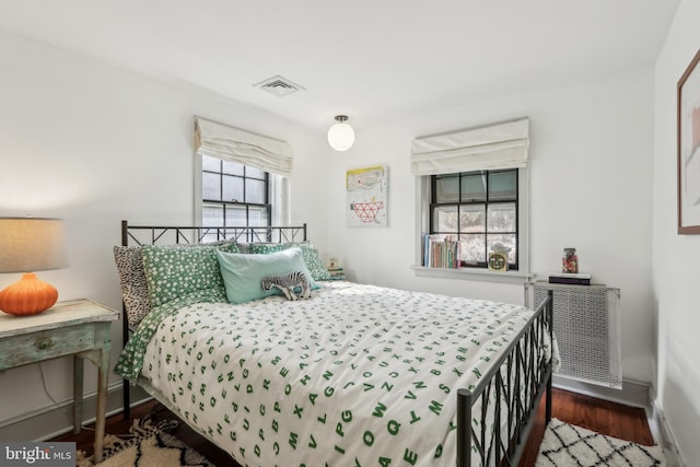 bedroom with baseboards, visible vents, and wood finished floors