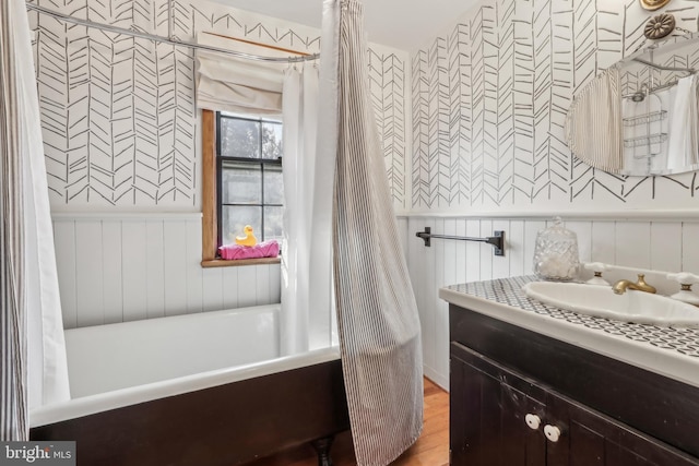 full bathroom featuring a bath, wainscoting, and vanity