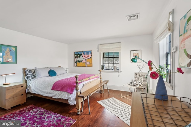 bedroom with visible vents, baseboards, and wood finished floors