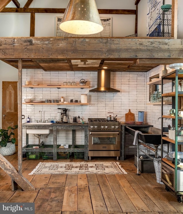 interior space featuring high end stove, wall chimney range hood, a towering ceiling, and hardwood / wood-style flooring