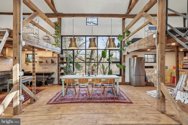 dining room featuring plenty of natural light, a high ceiling, and wood-type flooring