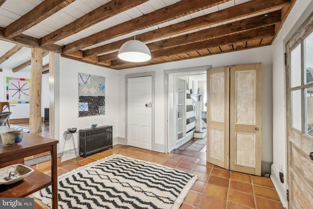 tiled entrance foyer featuring radiator, a healthy amount of sunlight, beamed ceiling, and wooden ceiling